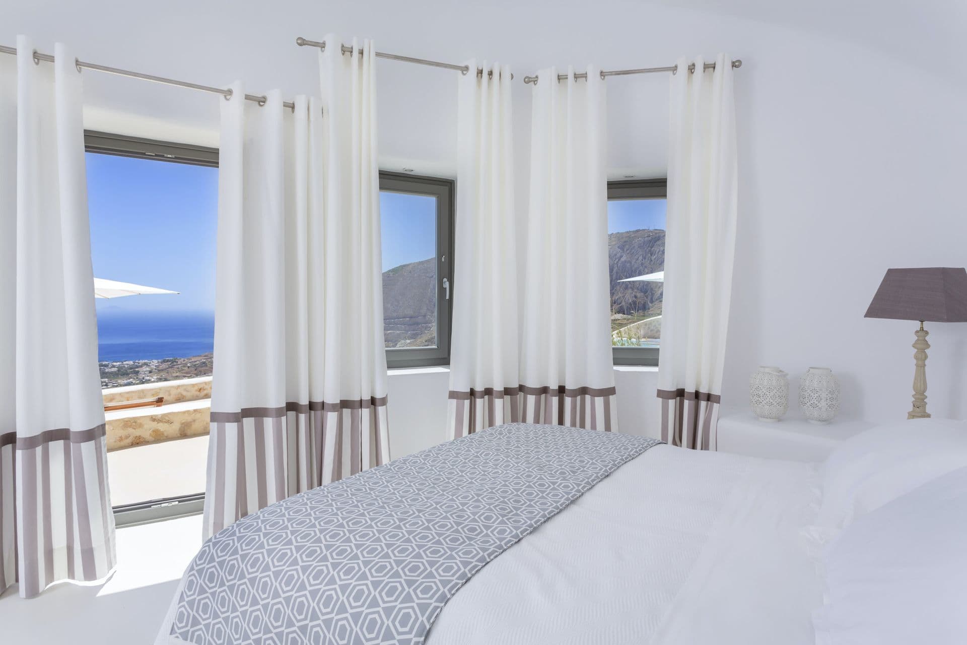 Master bedroom with windows framing the sea and hills at Calypso Dream, Santorini