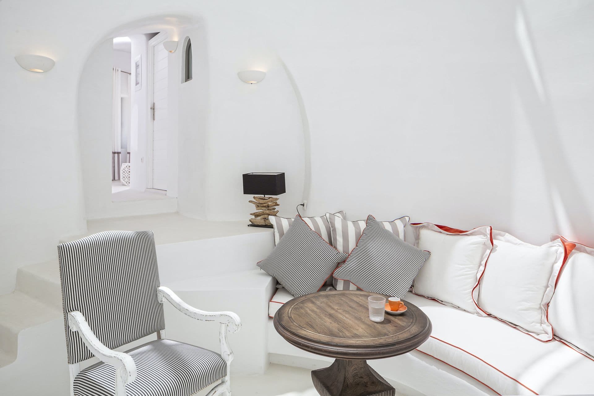 White cave sitting room with a sofa and armchair at Calypso Dream, Santorini