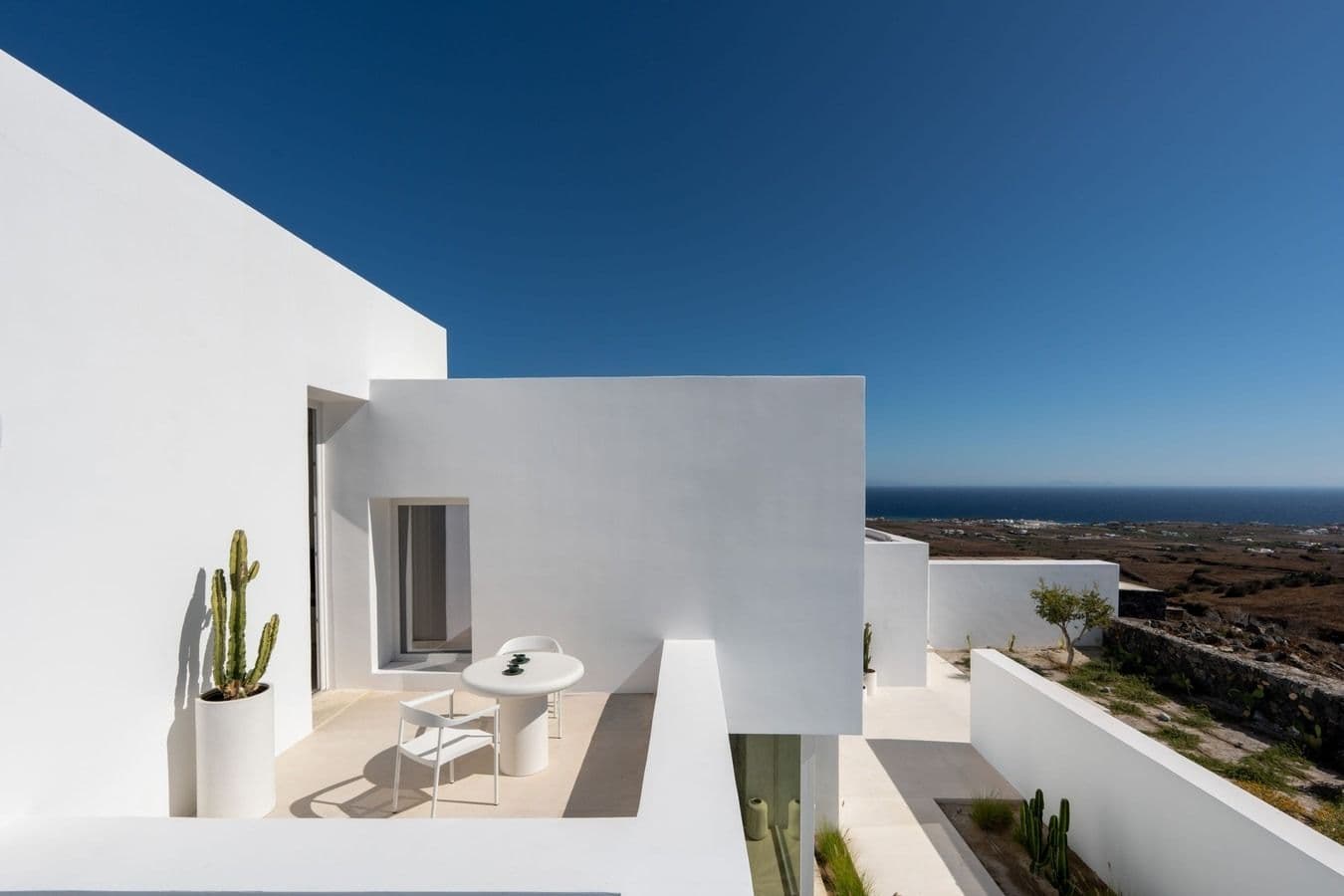 White cycladic villa exterior with cactus planting under a clear blue sky