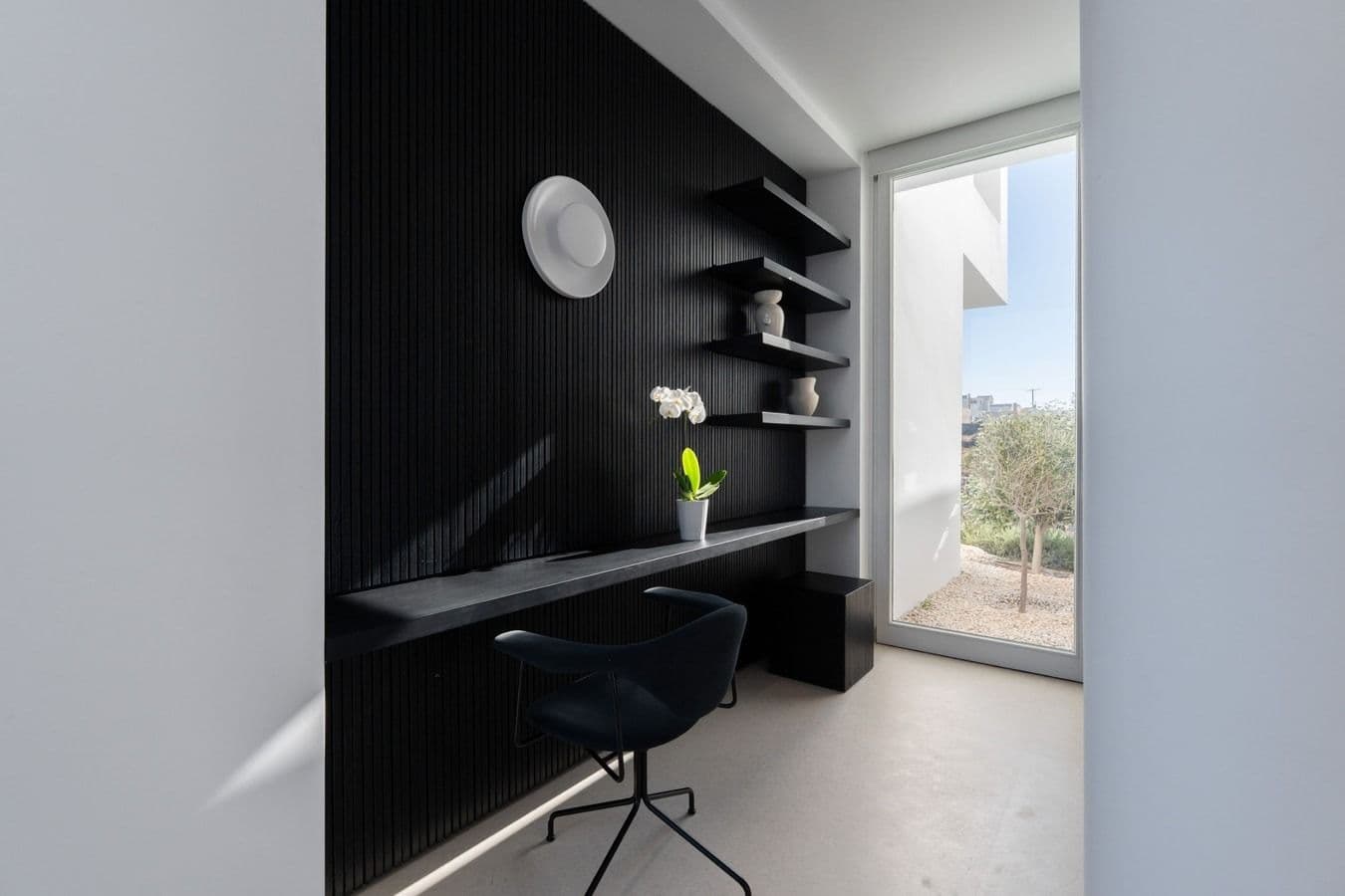 Home office nook with black shelving and desk beside a window