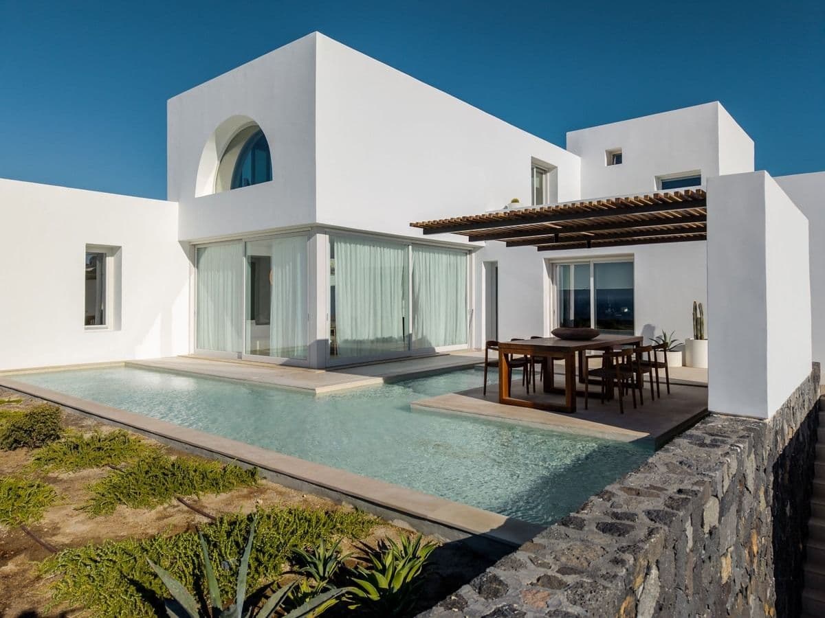 Pool with sun loungers and shaded dining area beside white villa walls