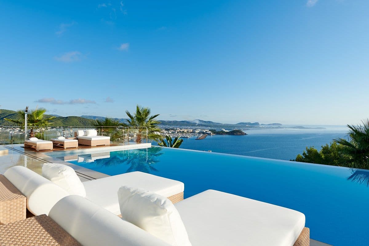 Infinity pool and white day beds overlooking the bay and town at Blue Sea Bliss, Ibiza