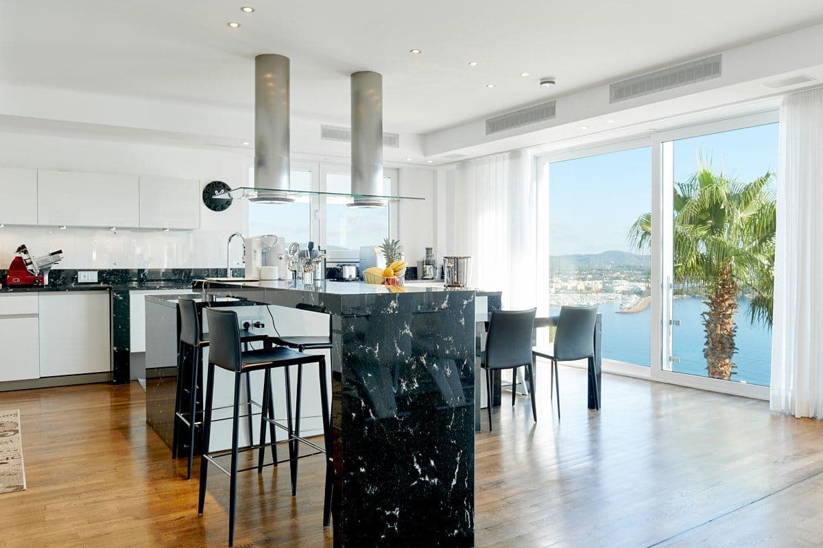 Kitchen island and breakfast bar beside sea-view windows at Blue Sea Bliss, Ibiza