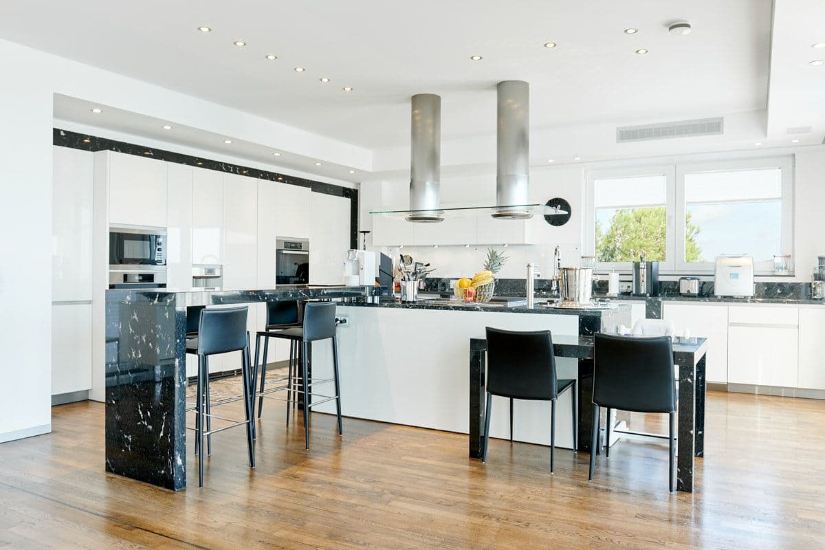 White kitchen with a black-marble island and breakfast bar at Blue Sea Bliss, Ibiza