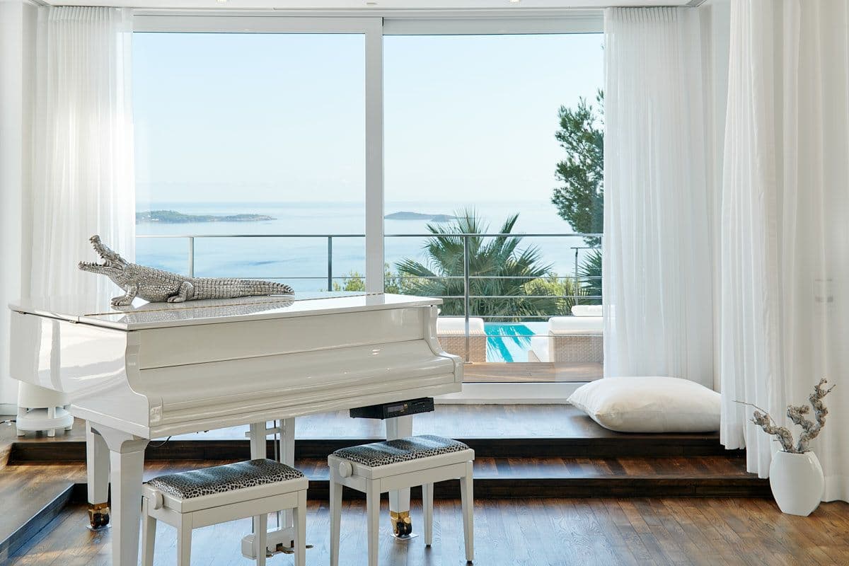 Sitting room with a white grand piano and sea views at Blue Sea Bliss, Ibiza