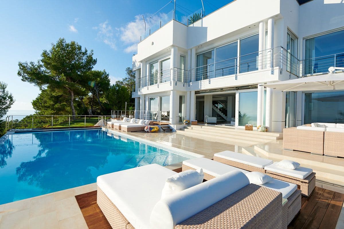 Poolside deck with loungers alongside the white villa at Blue Sea Bliss, Ibiza