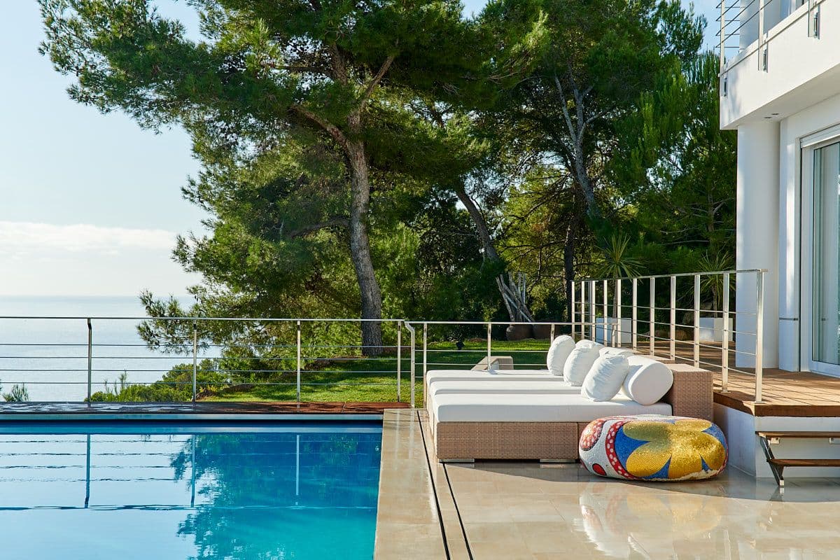 Pool and day beds framed by pines with a sea view at Blue Sea Bliss, Ibiza