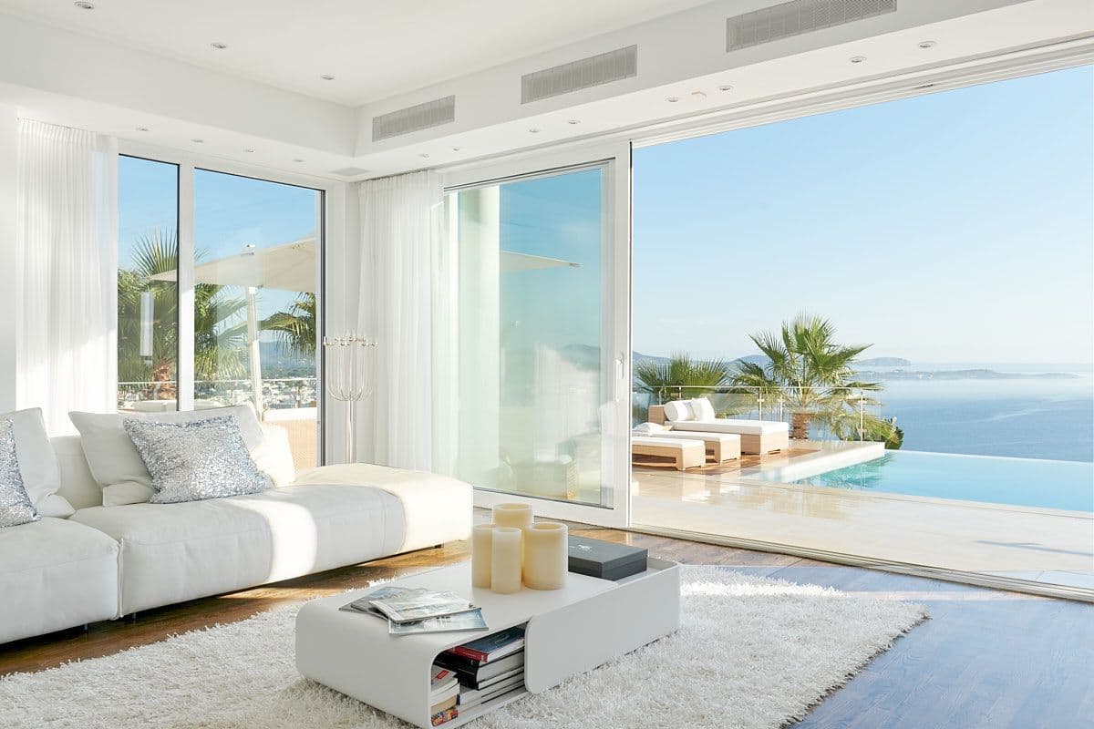 White lounge with sliding doors onto the pool and sea at Blue Sea Bliss, Ibiza
