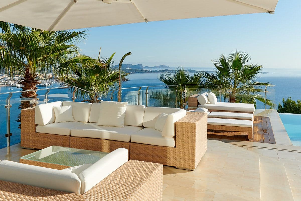 Sun terrace with a white sofa and palms overlooking the sea at Blue Sea Bliss, Ibiza
