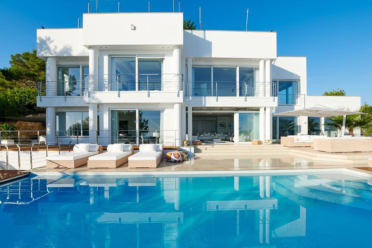 Modern white villa facade above a large pool and sun terrace at Blue Sea Bliss, Ibiza