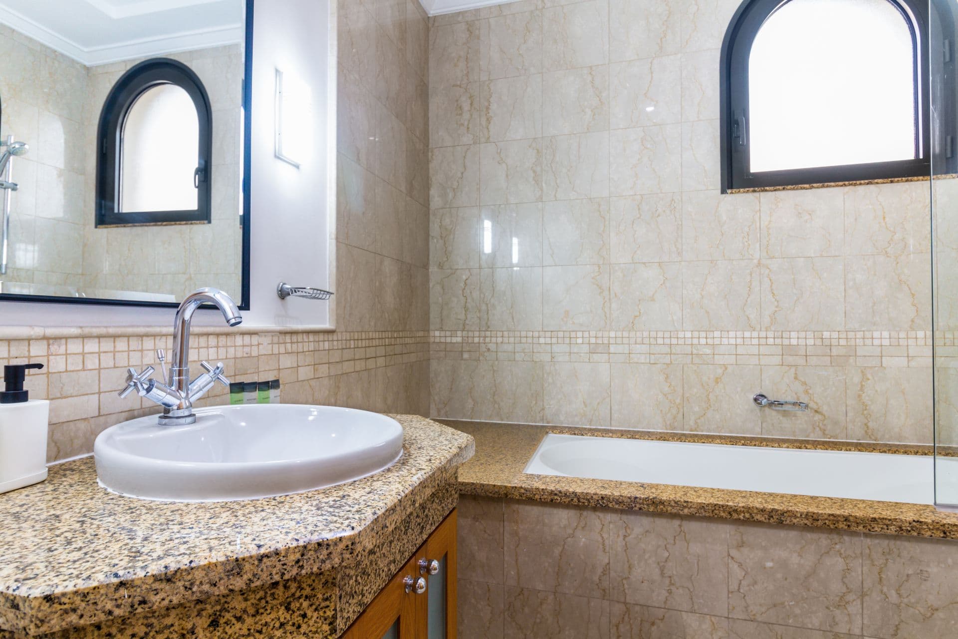 Marble bathroom with corner bathtub and arched window