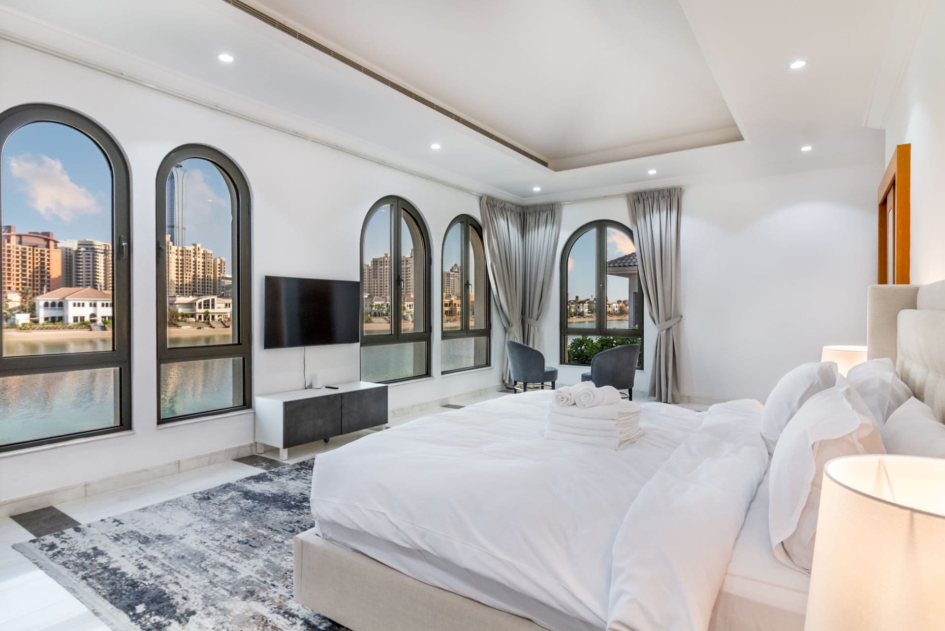 Bedroom with arched windows overlooking the waterway and skyline