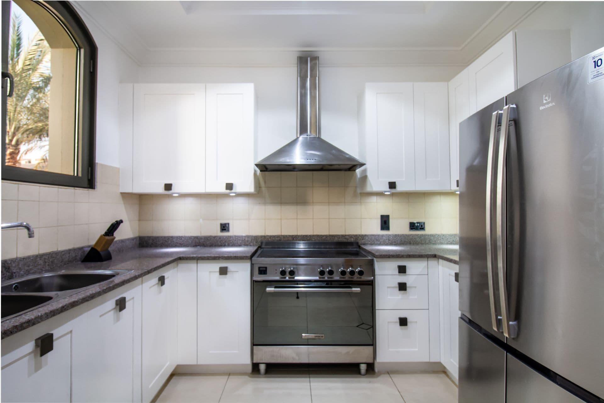 White fitted kitchen with stainless steel range and fridge