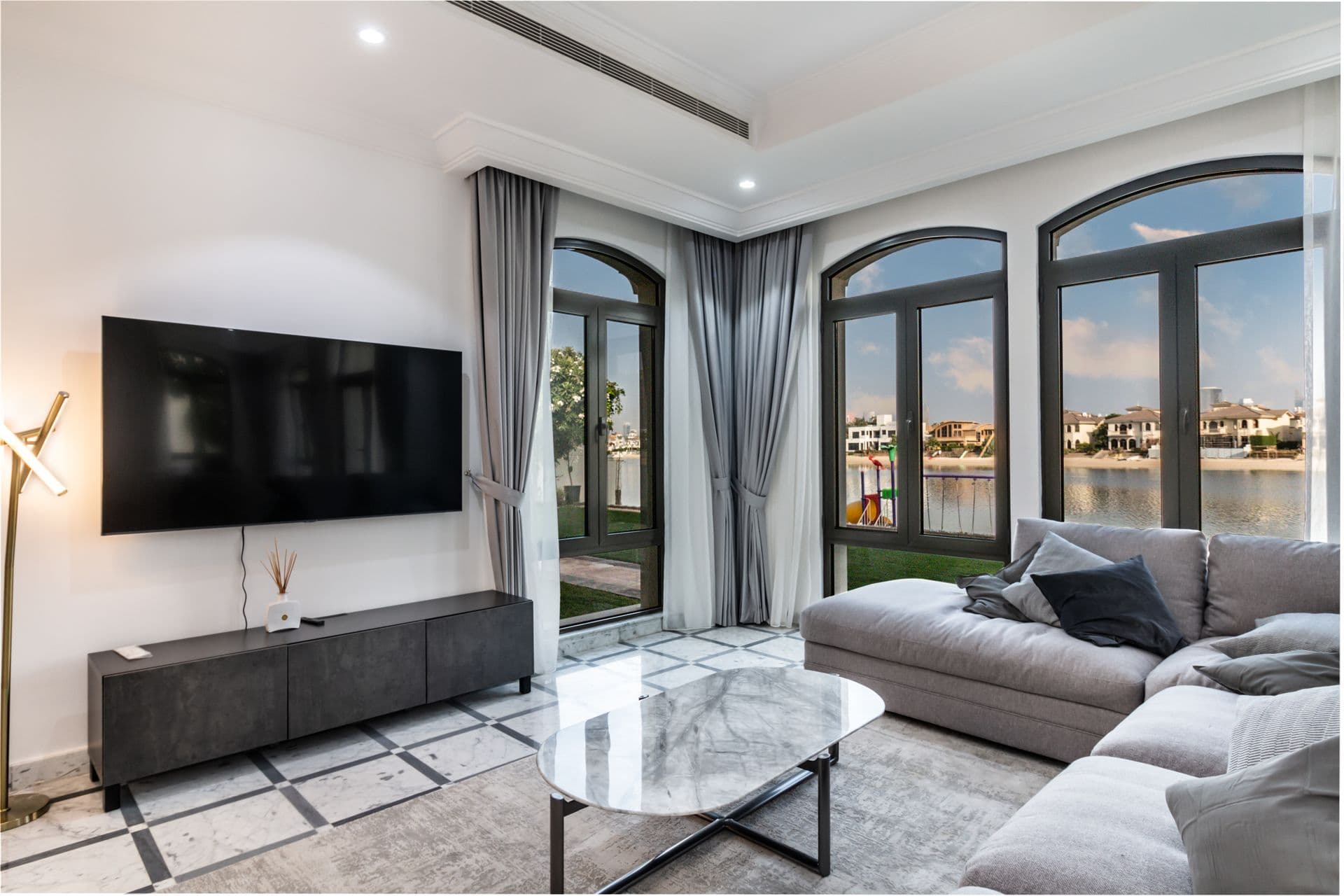Living room with grey sectional sofa and arched waterside windows