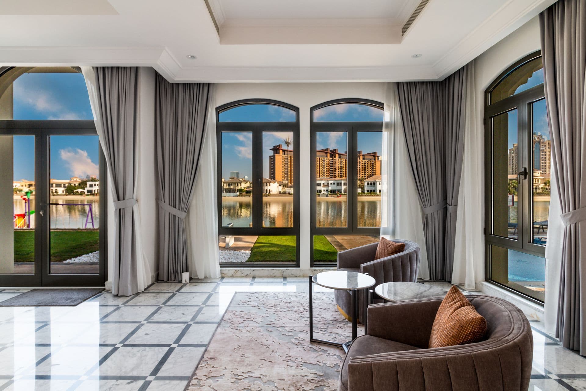 Lounge seating beside arched windows framing the waterside view