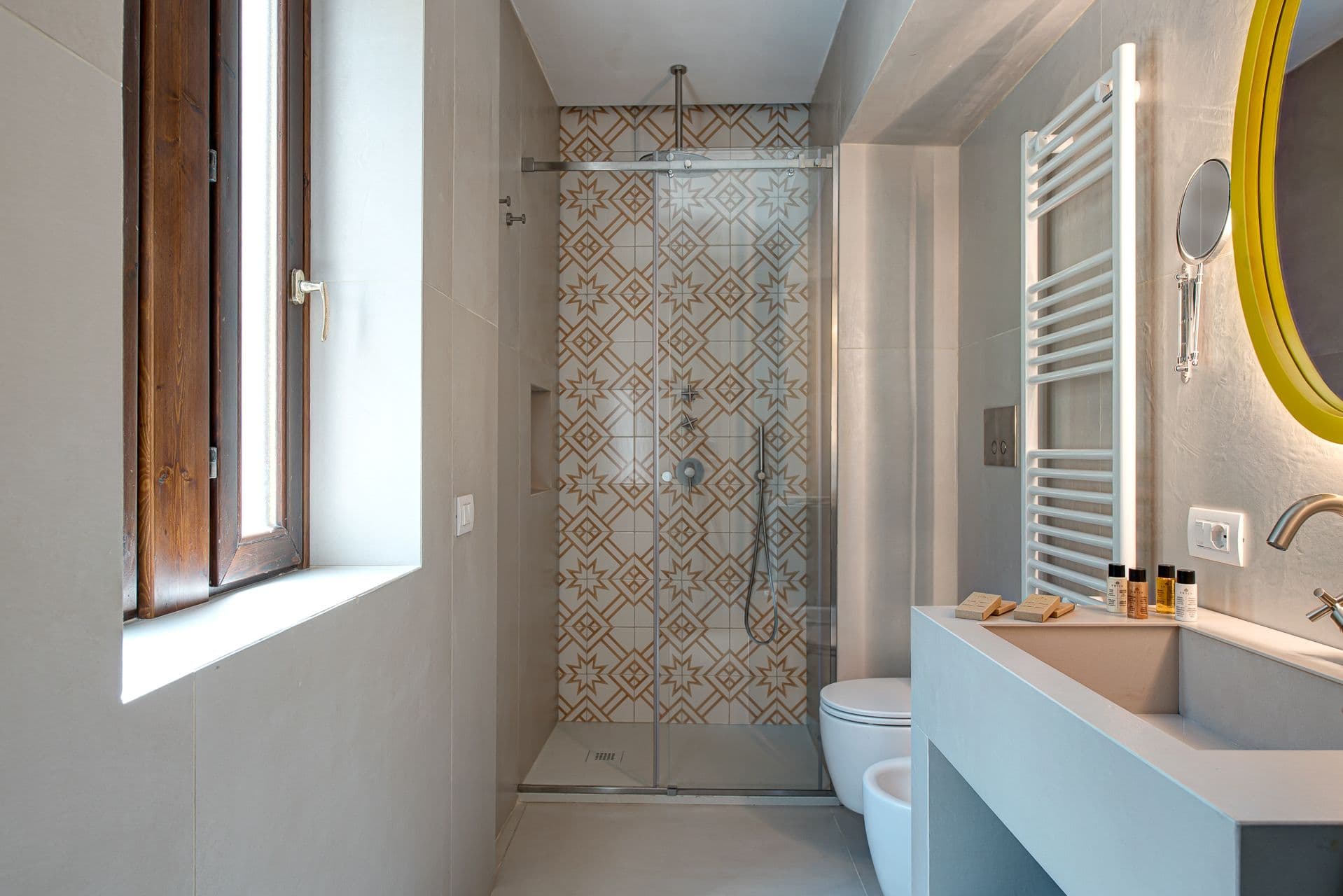 Ensuite bathroom with a glass shower, patterned tiles and a heated towel rail at Mount of Love