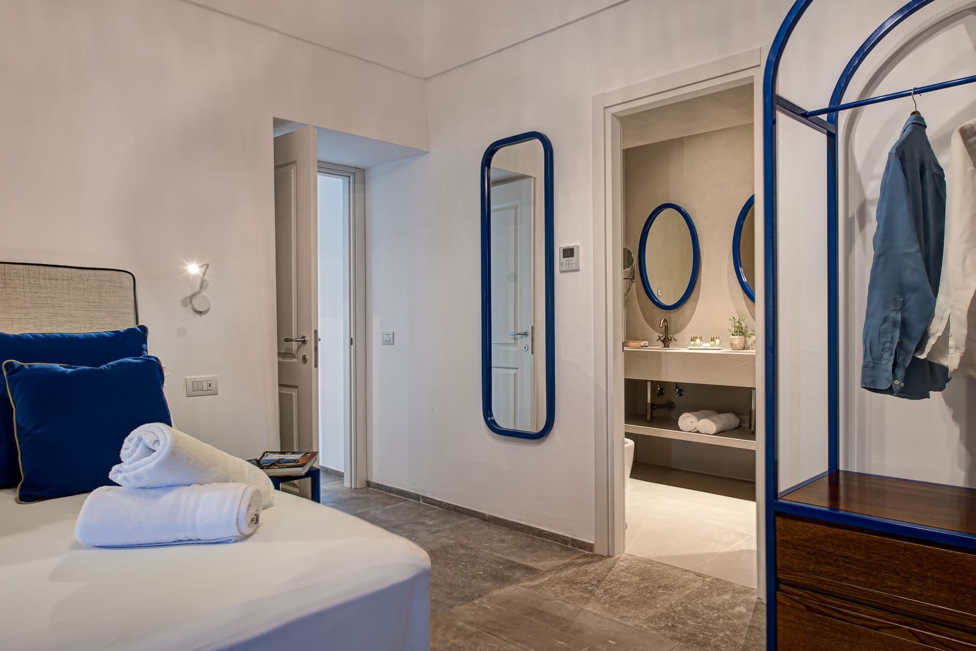 White bedroom with cobalt blue cushions and a mirrored dressing area at Mount of Love