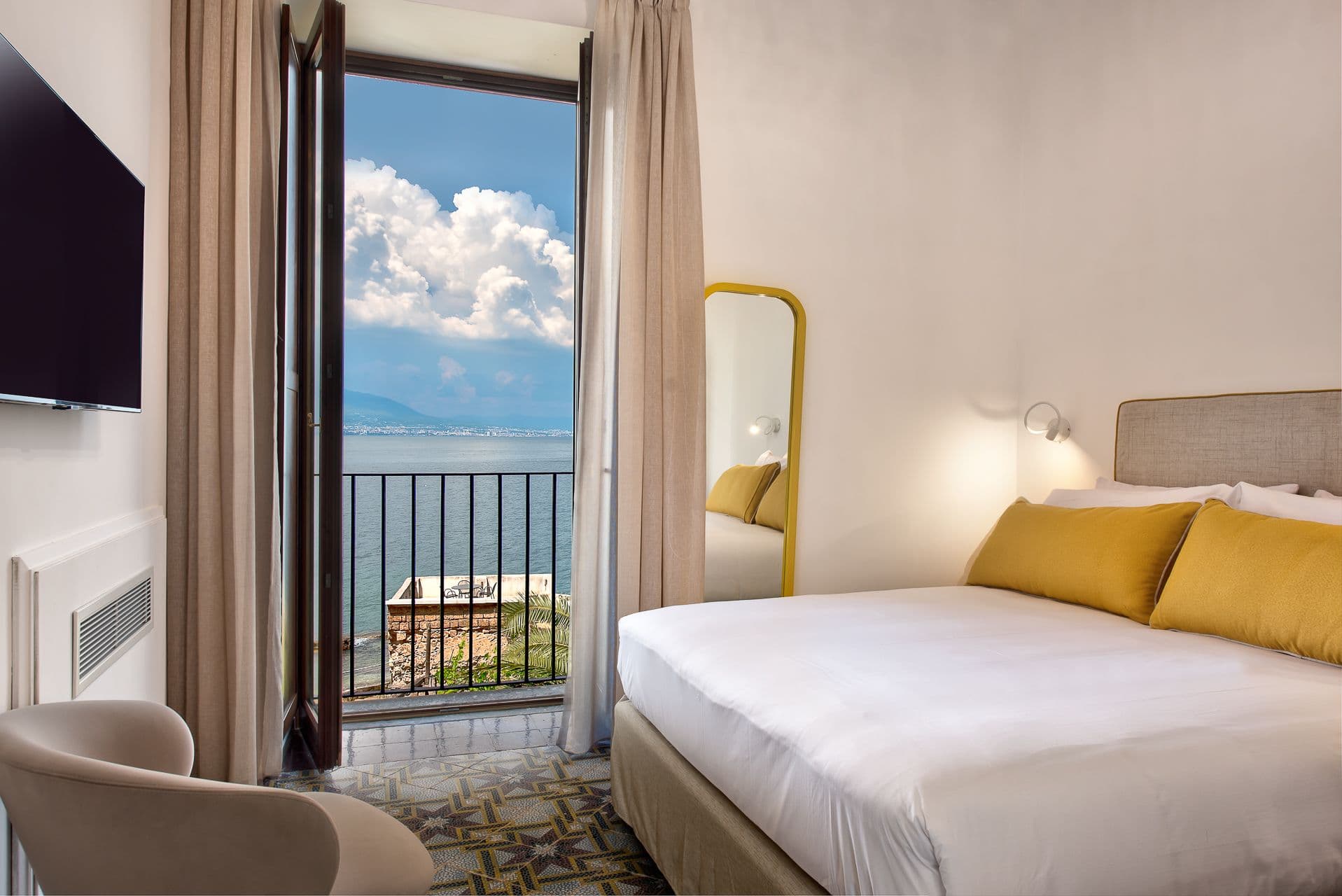 Bedroom with mustard yellow cushions and a window framing the sea view at Mount of Love