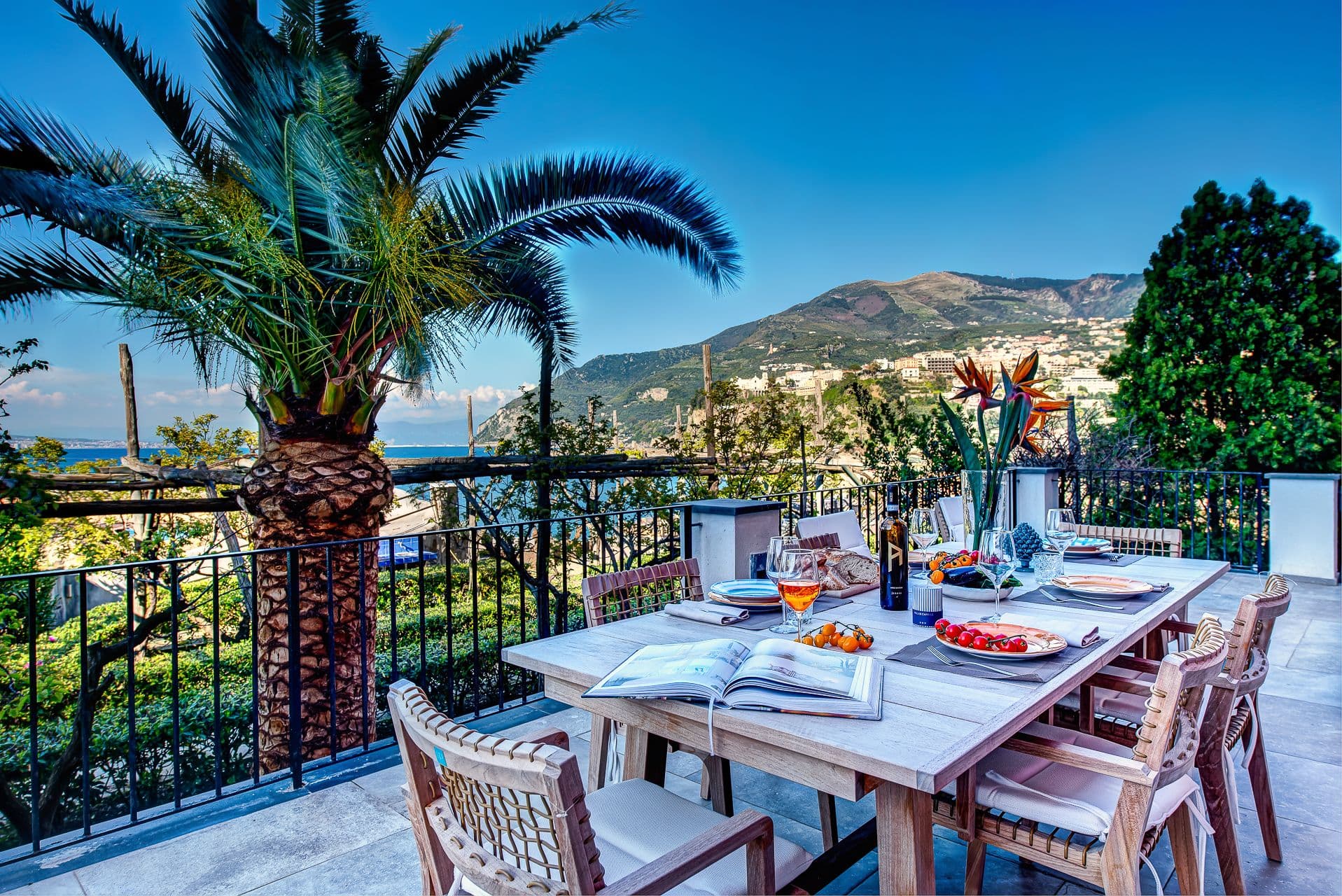 Outdoor dining table set beneath a palm tree with mountain and sea views at Mount of Love