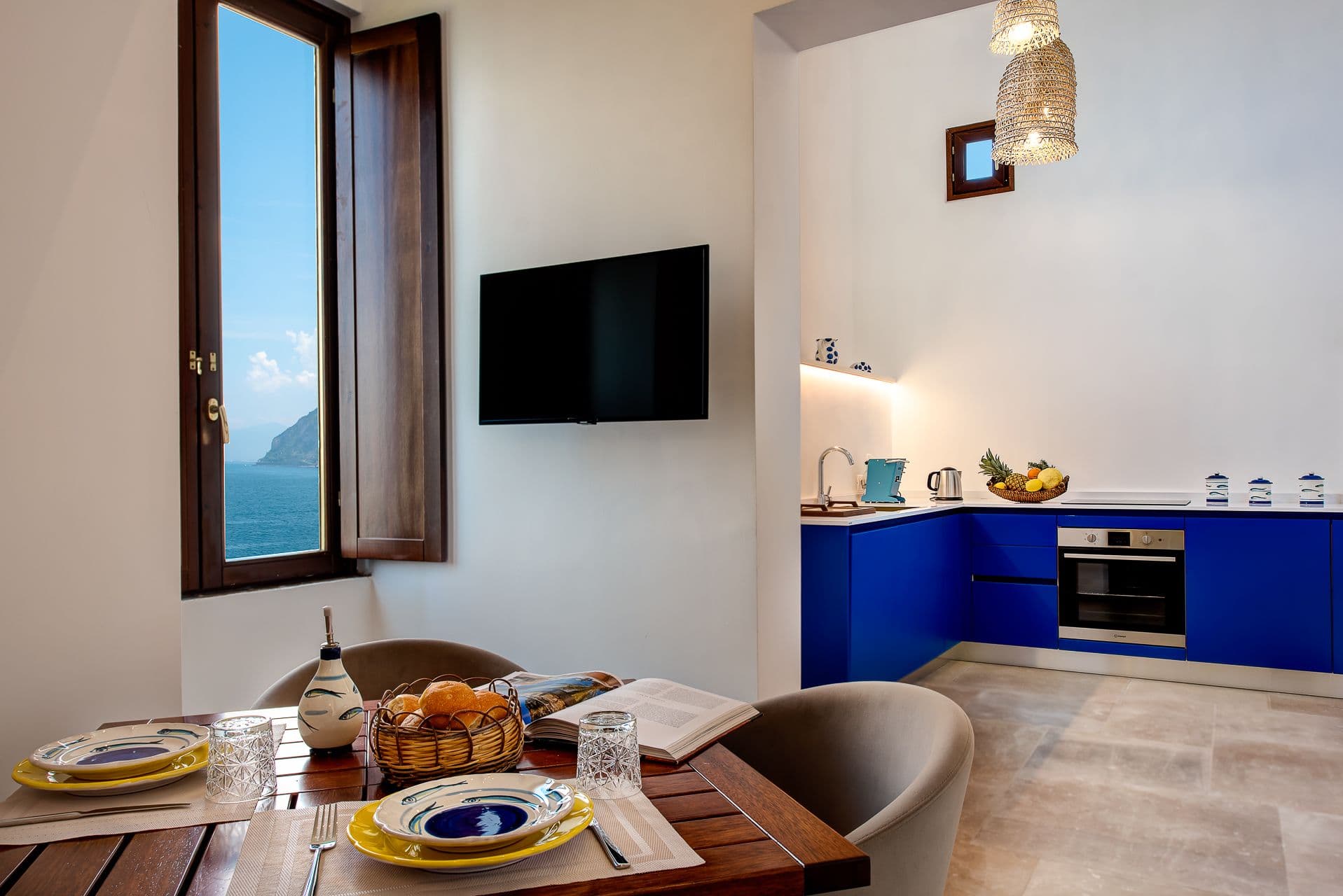Open plan living and dining area with a wooden table and sea glimpses at Mount of Love