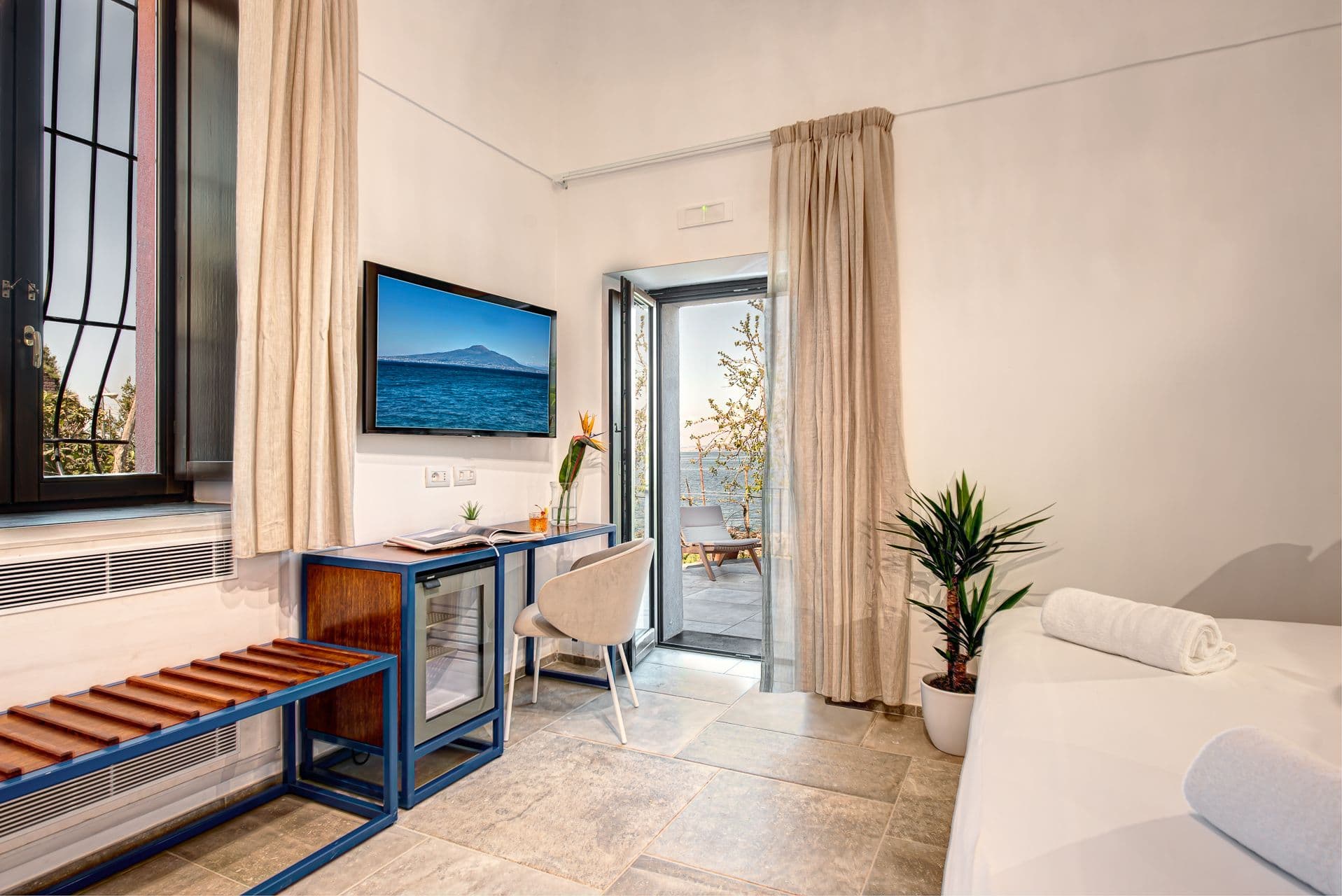 Compact study nook with a desk and armchair beside glass doors opening to the terrace at Mount of Love