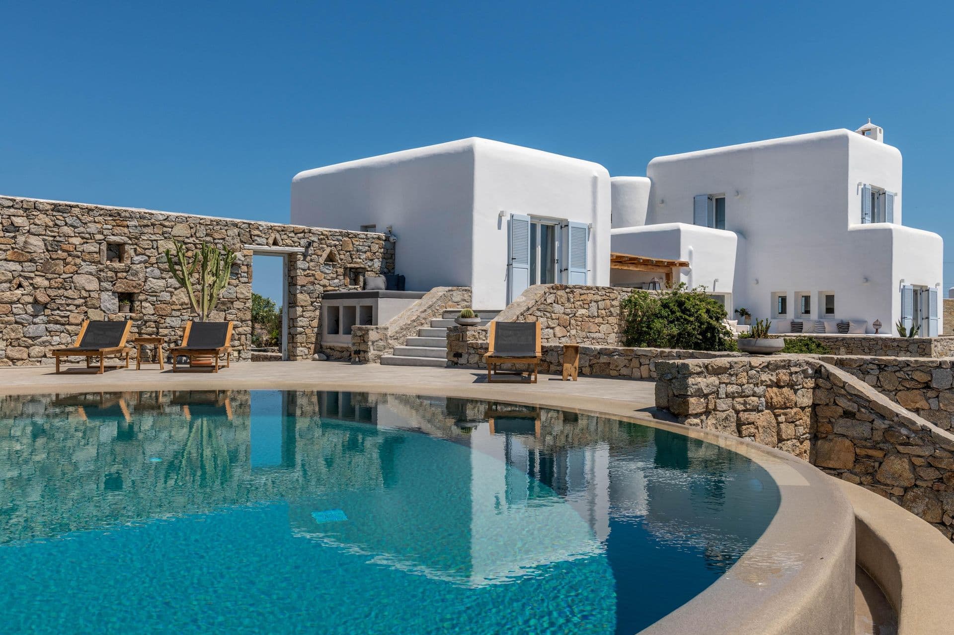 Whitewashed Cycladic villa exterior with curved pool at Party Invitation, Mykonos