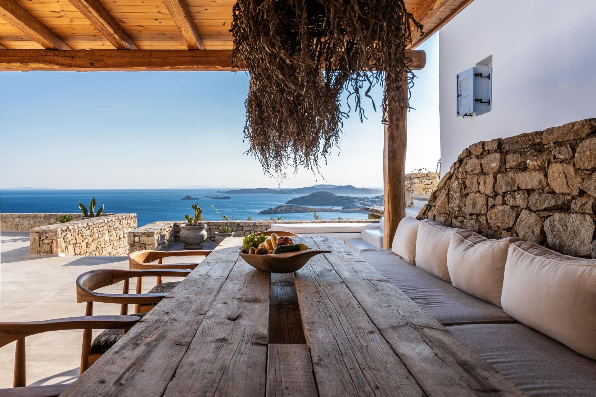 Long outdoor dining table under a pergola with sea views at Party Invitation