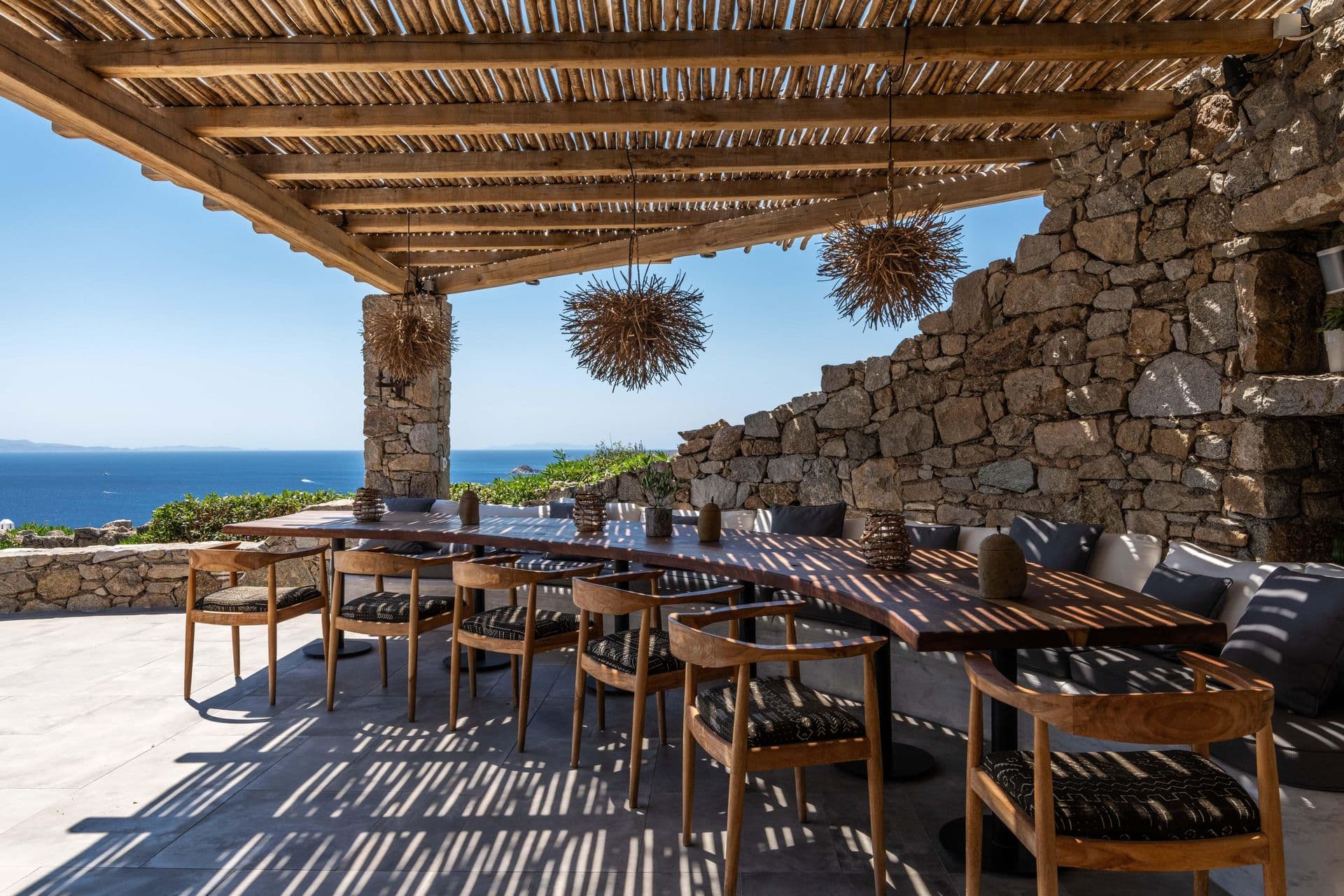 Shaded pergola dining area with stone columns at Party Invitation villa