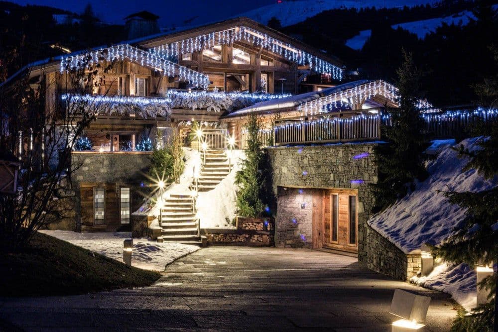 Timber and stone chalet lit at night in the snow at Mont d'Arbois, Megeve
