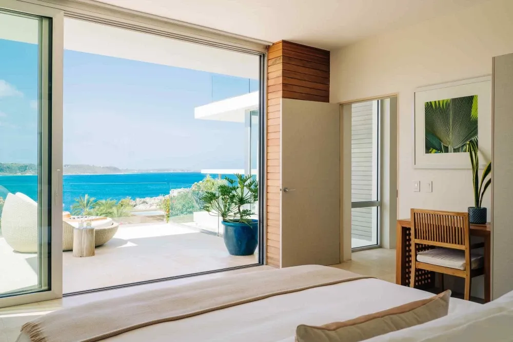 Bedroom opening to a private sea-view terrace with a daybed at Little Bay Villas