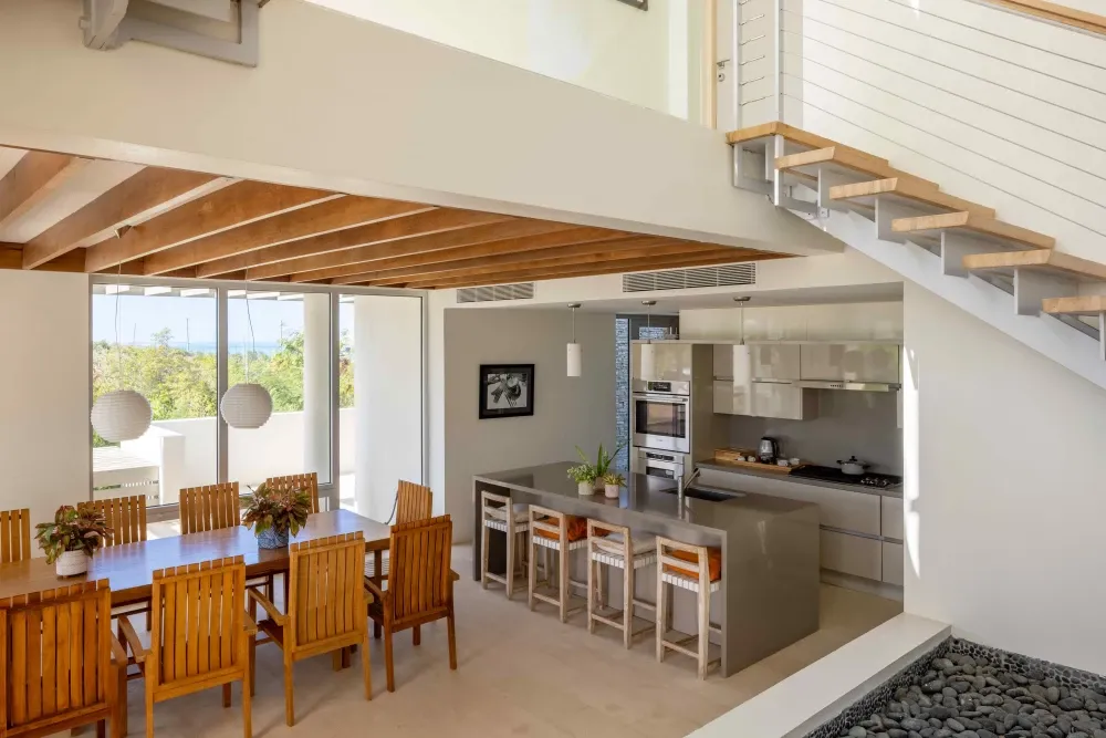 Open-plan kitchen and dining area under a timber-beamed ceiling at Little Bay Villas