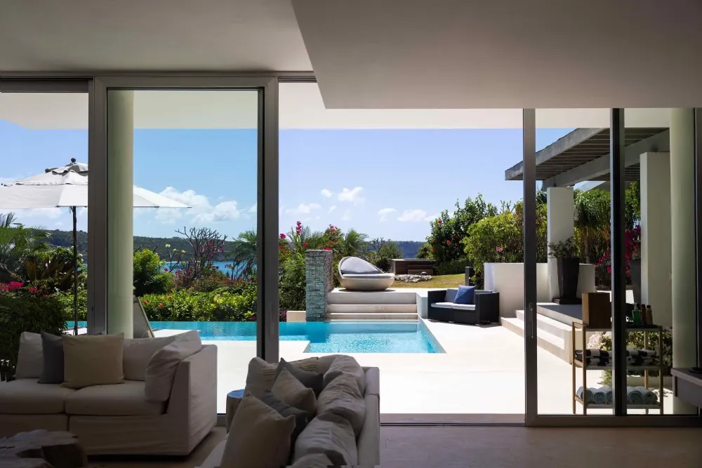 Living room looking out through glass to the pool and cove at Little Bay Villas