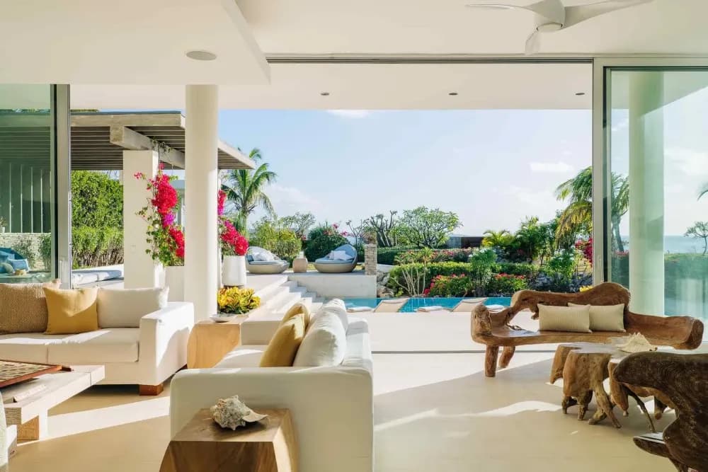 Open-plan living room with driftwood furniture opening to the pool and sea