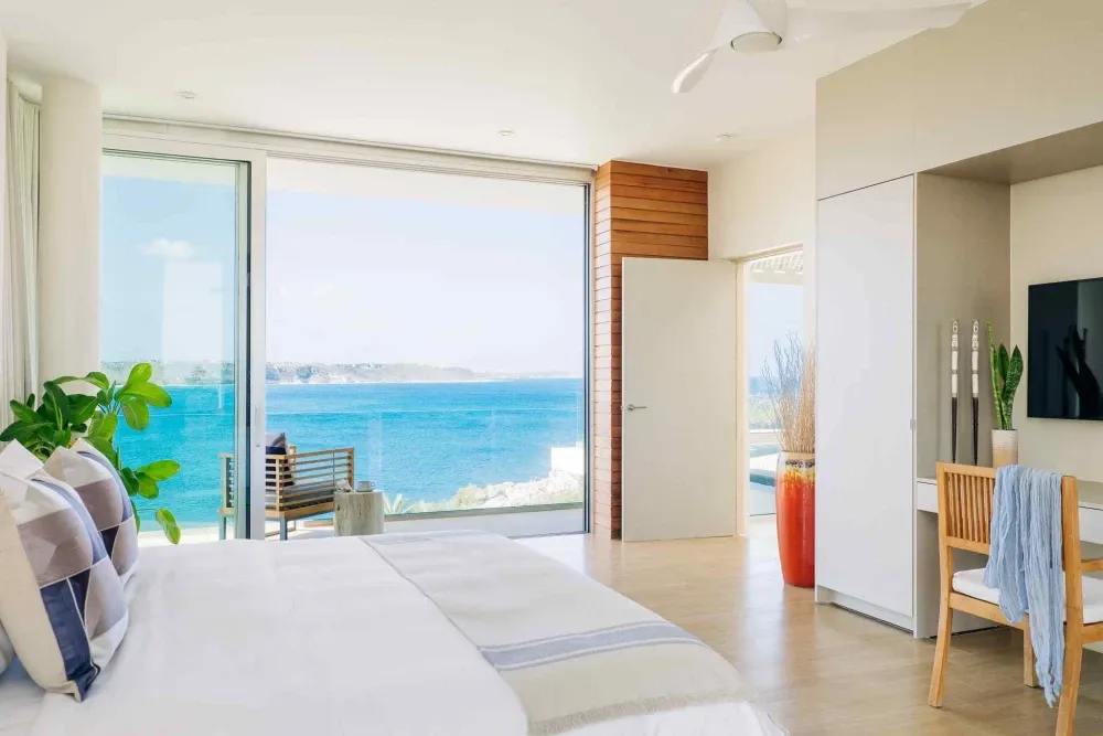 Master bedroom with floor-to-ceiling glass over the turquoise sea at Little Bay Villas