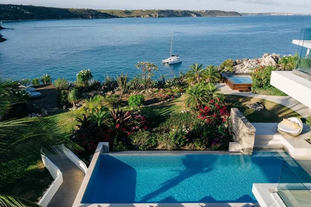 Infinity pool overlooking a cove with a moored catamaran at Little Bay Villas
