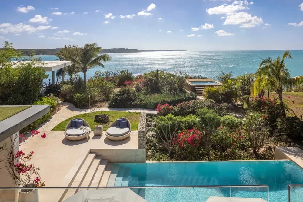 Poolside daybeds and gardens with elevated sea views at Little Bay Villas