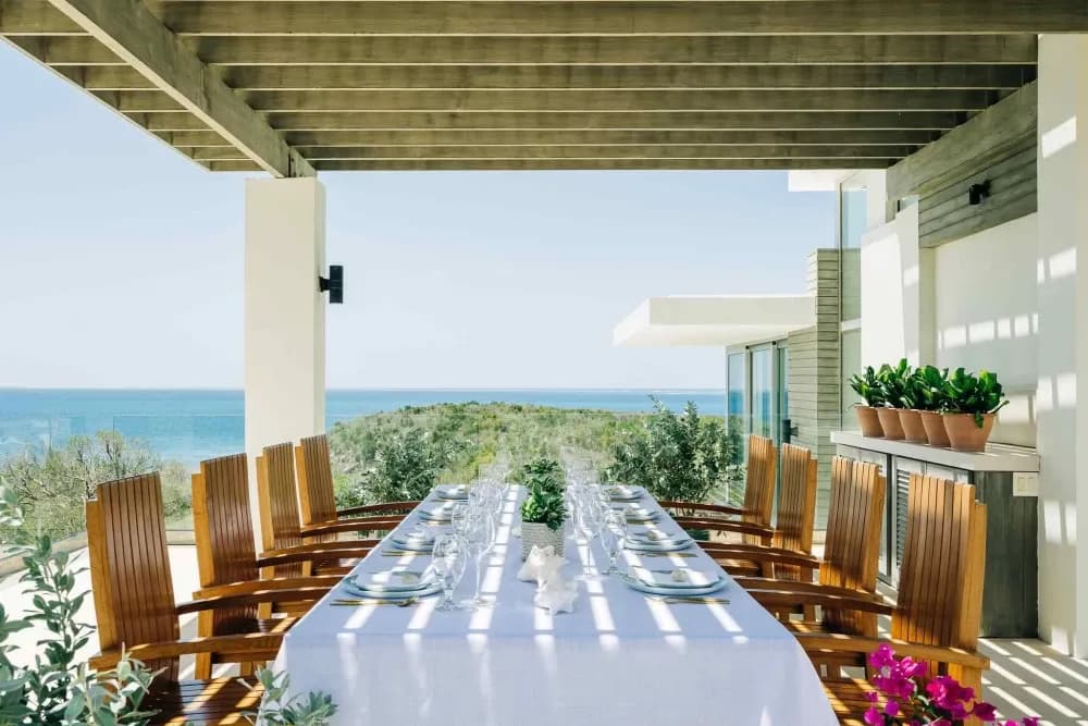 Covered terrace dining table set for ten with sea views at Little Bay Villas