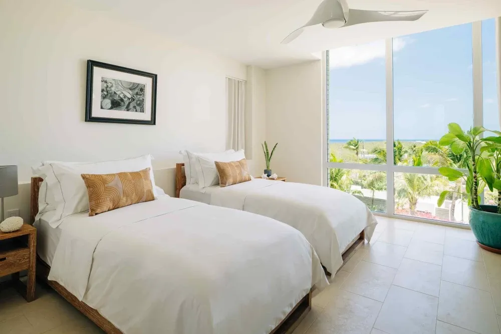 Twin bedroom with a sea view and floor-to-ceiling glass at Little Bay Villas