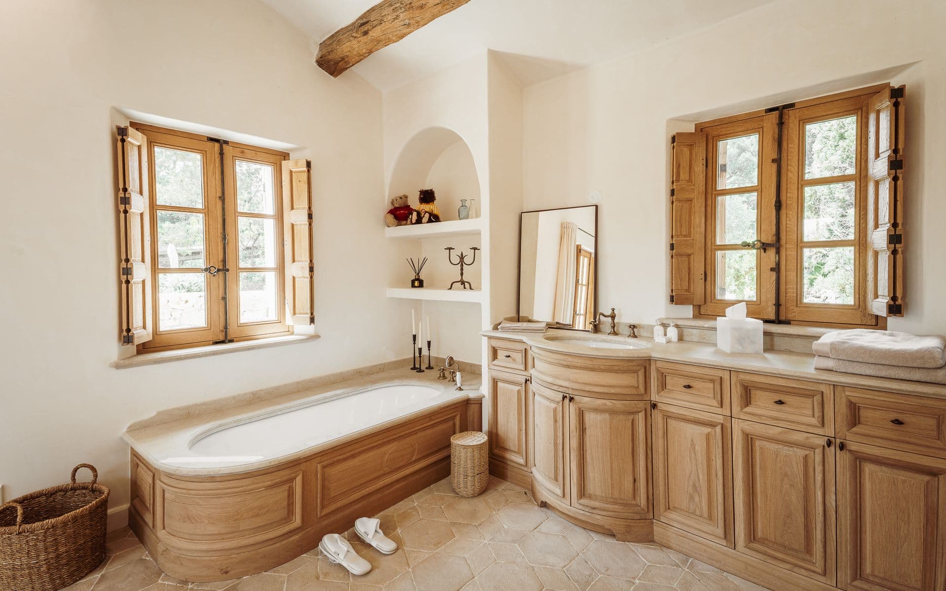 Bathroom with wood-panelled bathtub and double vanity beneath shuttered windows