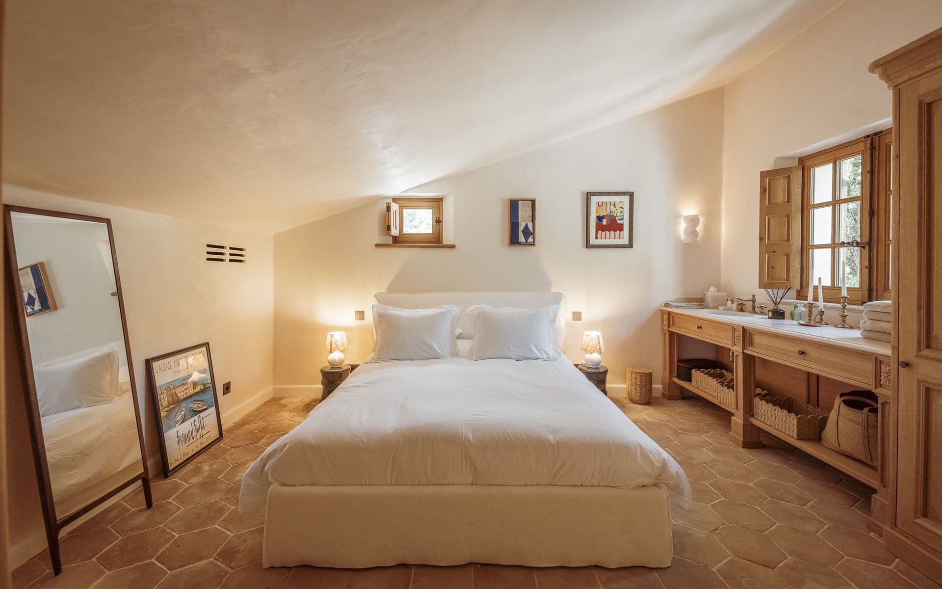 Bedroom with white bedding, terracotta floor and full-length mirror