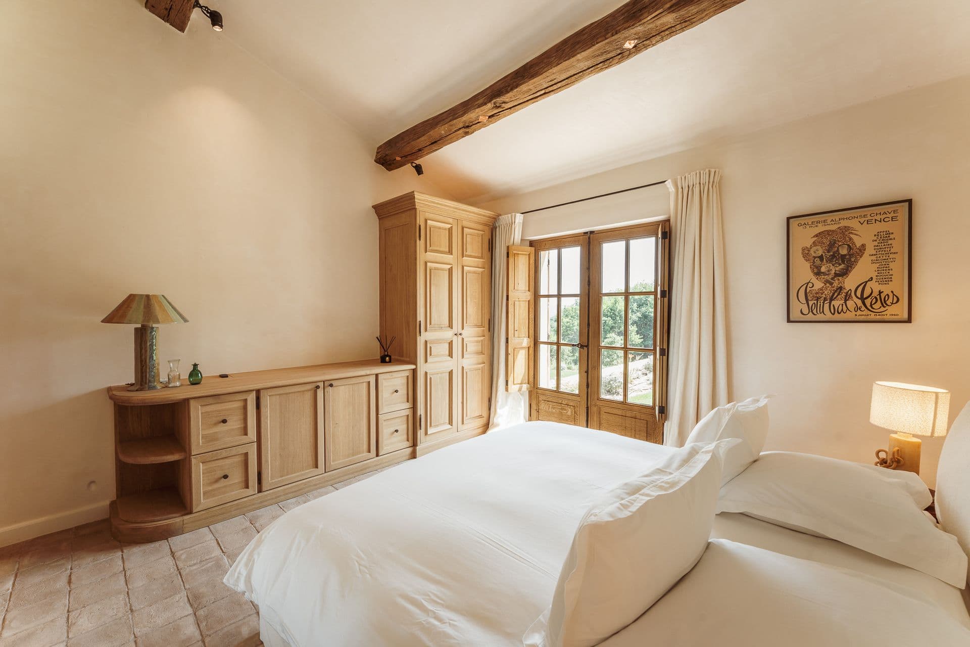 Bedroom with beamed ceiling, artwork and garden-facing doors