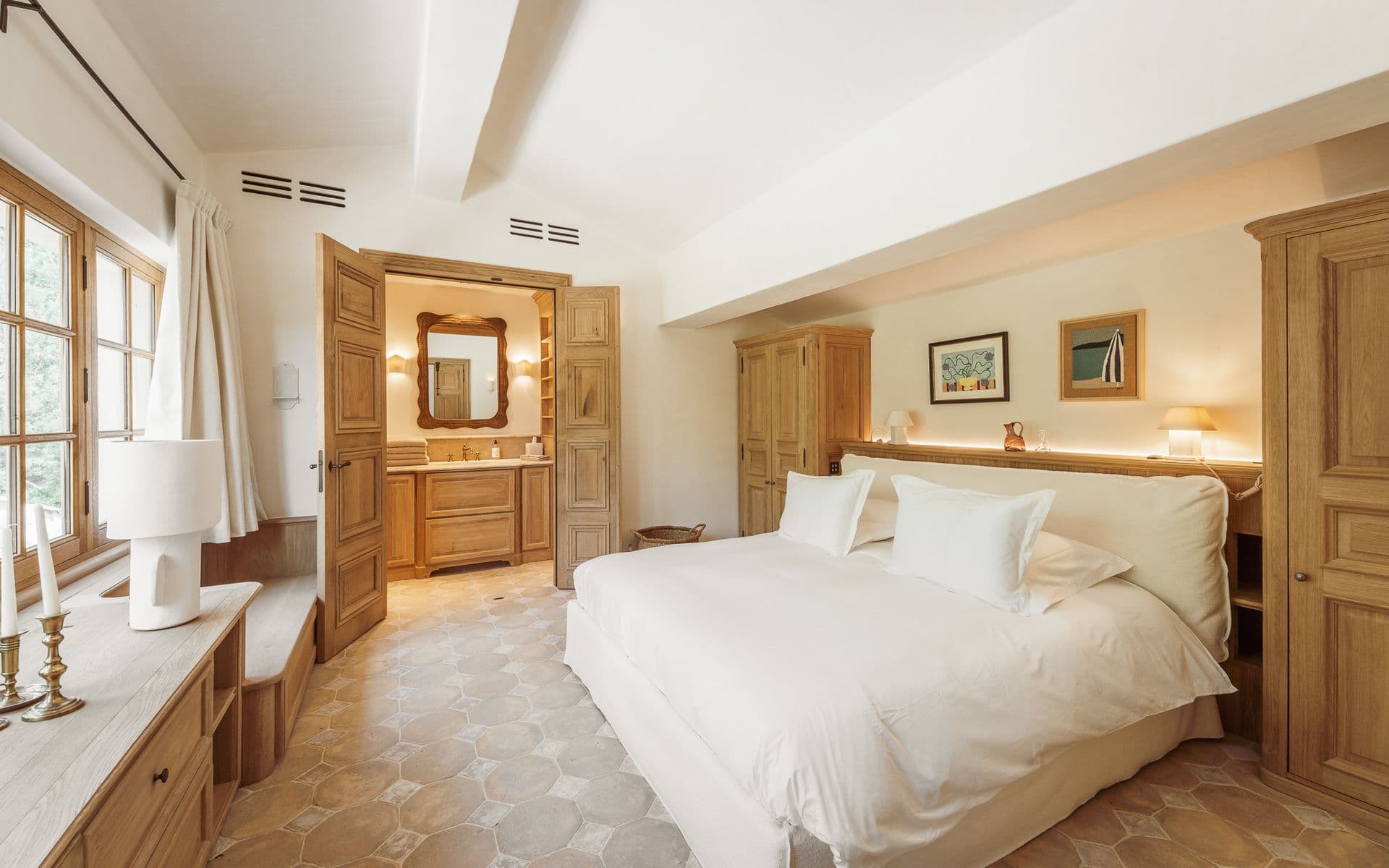 Beamed bedroom with white bed leading through to a private en-suite
