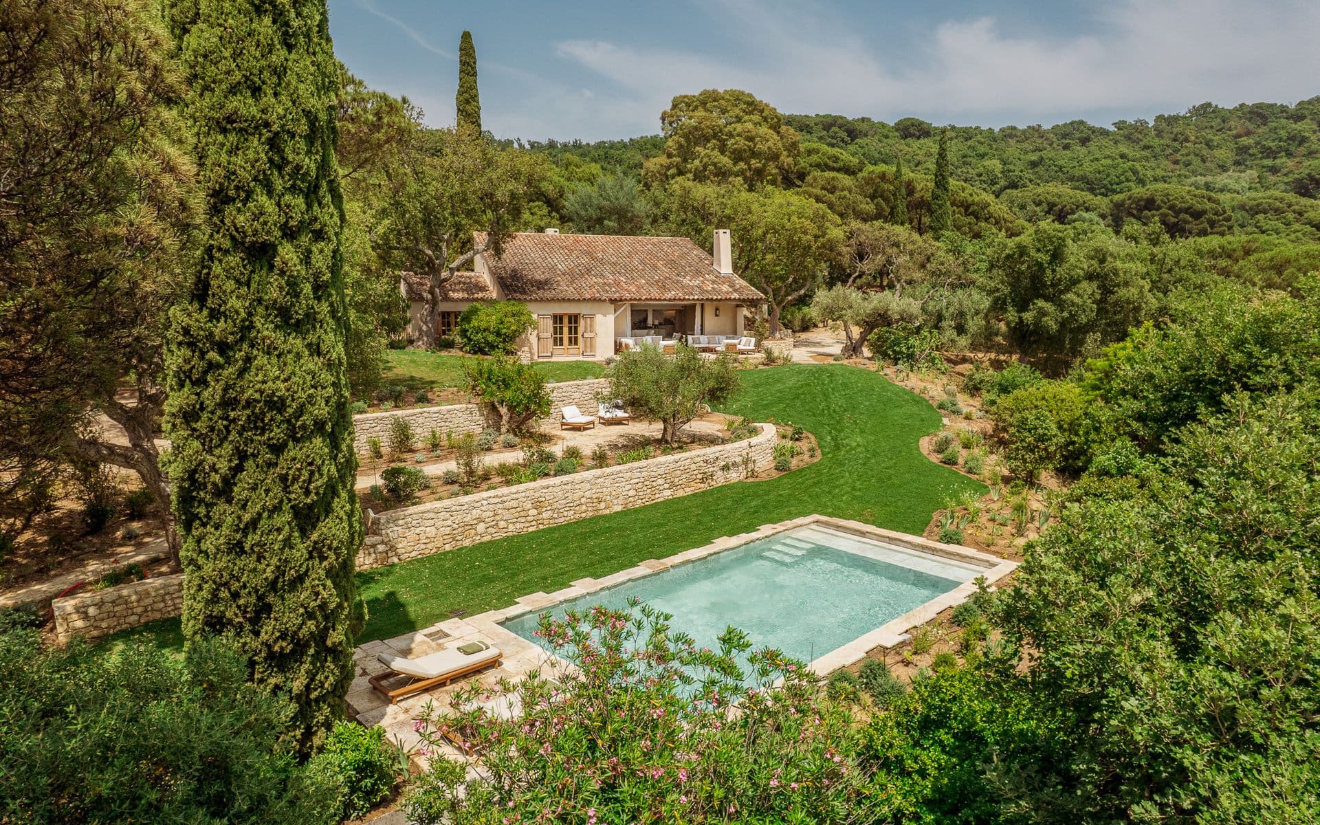 Aerial view of a Provencal stone villa with pool set among gardens and cypress trees