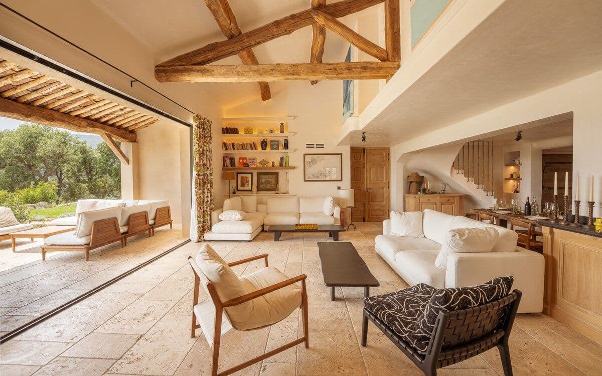 Living room with exposed beams opening onto the garden through folding doors