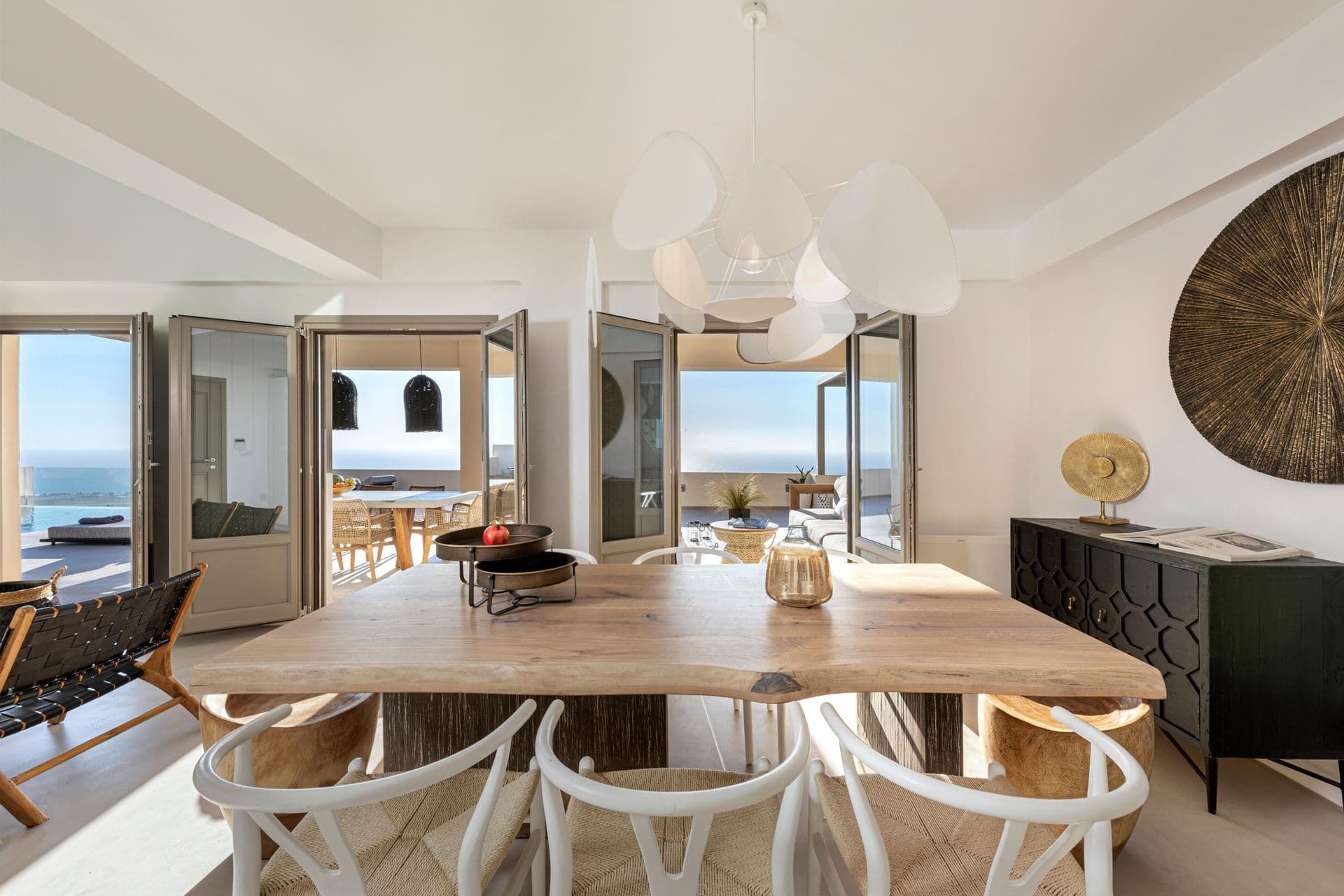 Dining room with a long wooden table and sea-view balcony doors at Smile Upon You