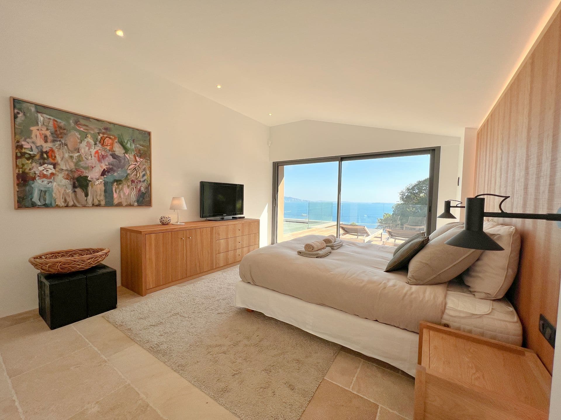 Oak-panelled double bedroom with a television and a sea view at Coastal Azure, Theoule-sur-Mer