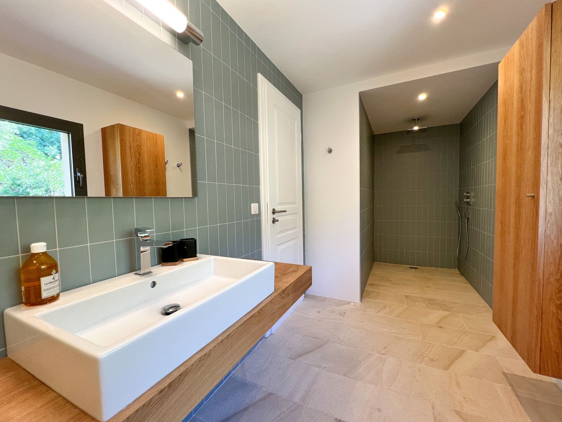 En-suite with a green-tiled wall, vessel basin and oak vanity at Coastal Azure, Theoule-sur-Mer