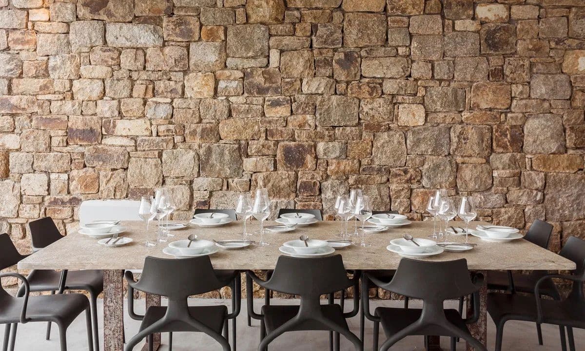 Outdoor stone dining table set for ten against a dry-stone wall at Ancient Azure Vistas, Mykonos