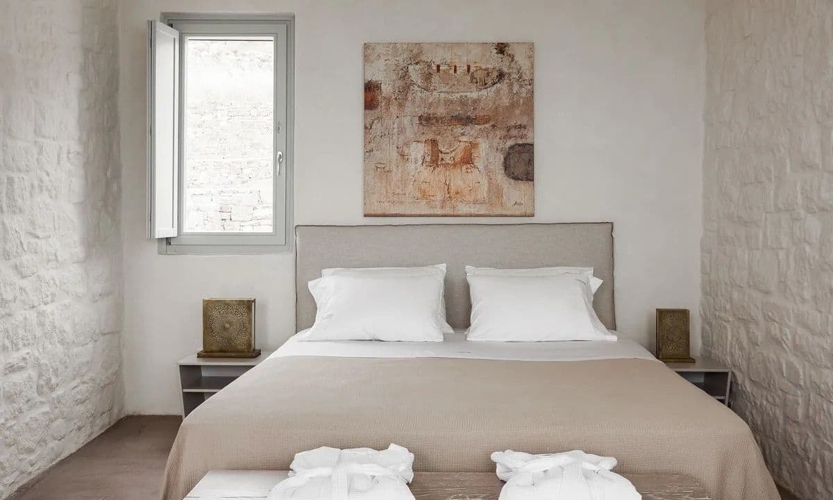 Double bedroom with whitewashed stone walls and a shuttered window at Ancient Azure Vistas, Mykonos