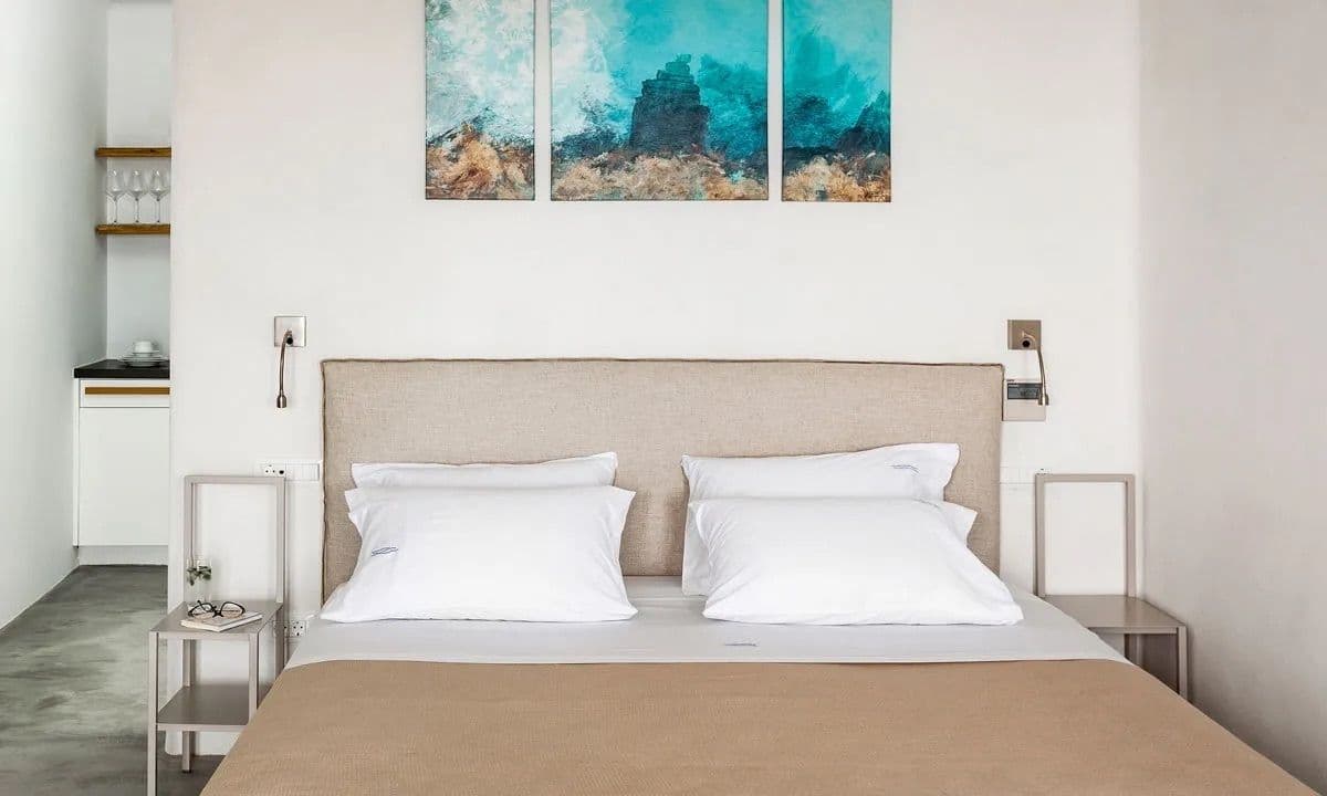 Double bedroom with a beige headboard and a sea-toned triptych at Ancient Azure Vistas, Mykonos